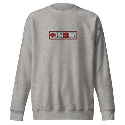 A carbon gray crewneck sweatshirt featuring a rectangular chest graphic with the text 'IN2R' in white and red, flanked by a red maple leaf icon, set against a plain white background.