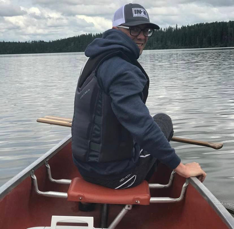 Trevor Williams portant un chandail à capuche et une casquette de camionneur IN2R en canoë