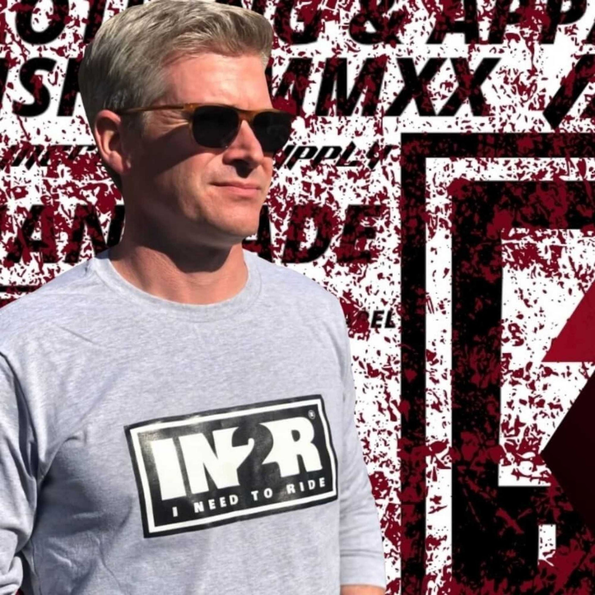 Dan O'Toole wearing sunglasses and a light gray t-shirt with a black and white 'IN2R I NEED TO RIDE' logo, standing in front of a graphic background with red and black text.