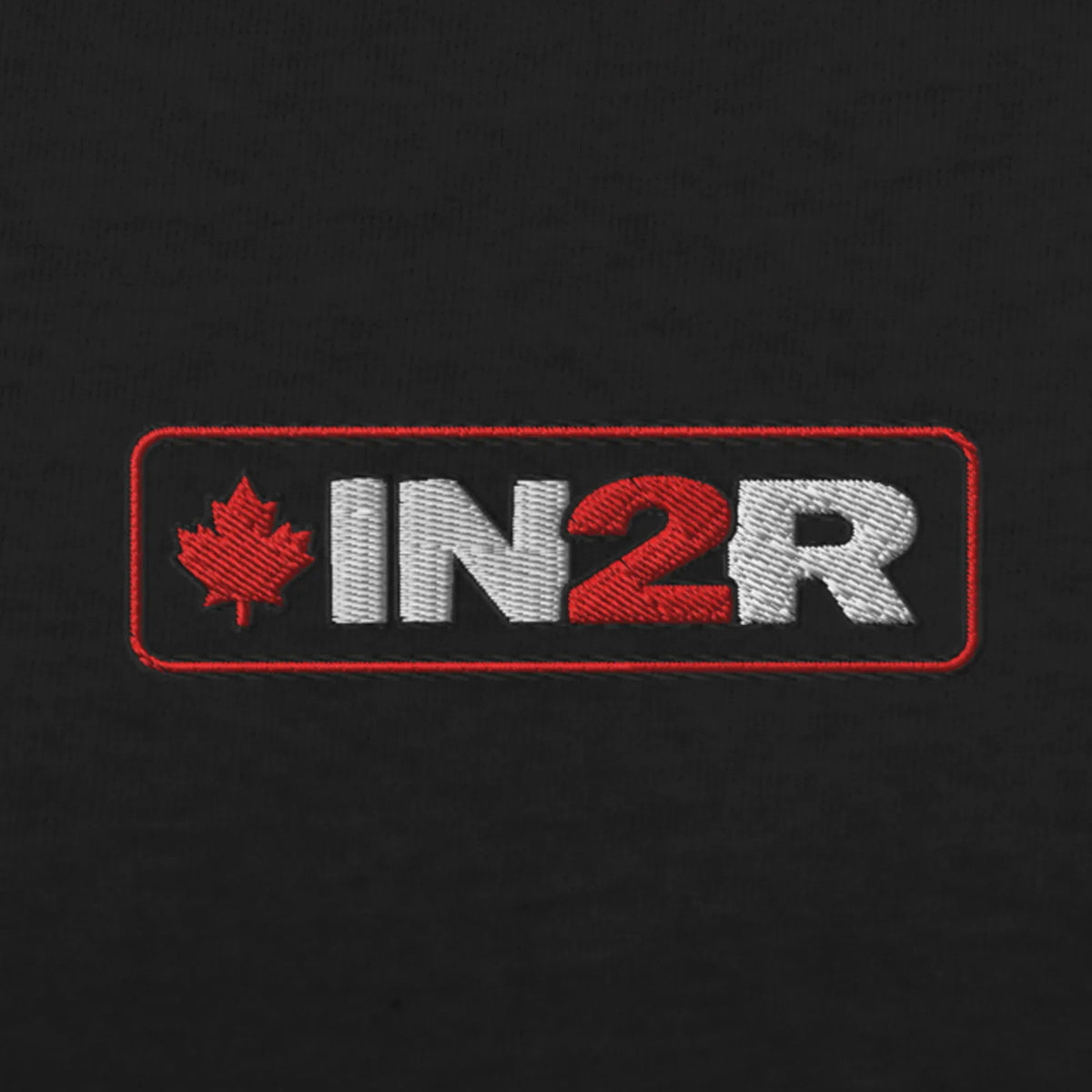 An embroidered rectangular patch on a black fabric background, featuring the text 'IN2R' in white and red with a red maple leaf on the left.