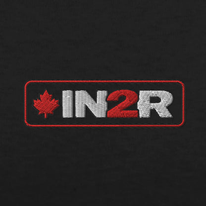 An embroidered rectangular patch on a black fabric background, featuring the text 'IN2R' in white and red with a red maple leaf on the left.