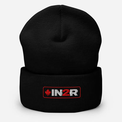 A black knit cuffed beanie hat featuring a rectangular embroidered logo patch on the front cuff with the text 'IN2R' in white and red, alongside a small red maple leaf, set against a light gray background.