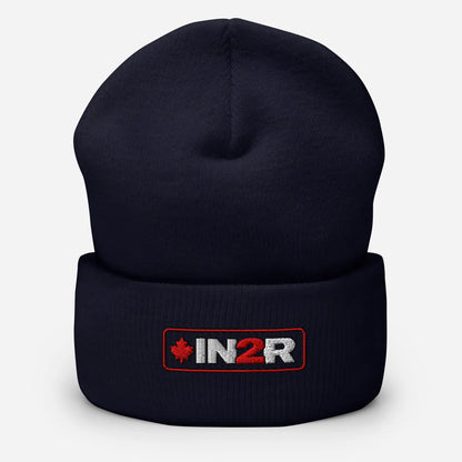 A dark navy blue knit beanie hat with a folded cuff, featuring an embroidered IN2R logo patch with a red maple leaf on the front, set against a light gray background.