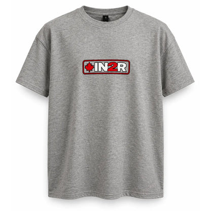 A heather gray short-sleeve t-shirt with a rectangular chest graphic that reads 'IN2R' in white over a red background, flanked by a red maple leaf icon, shown on a plain white background.