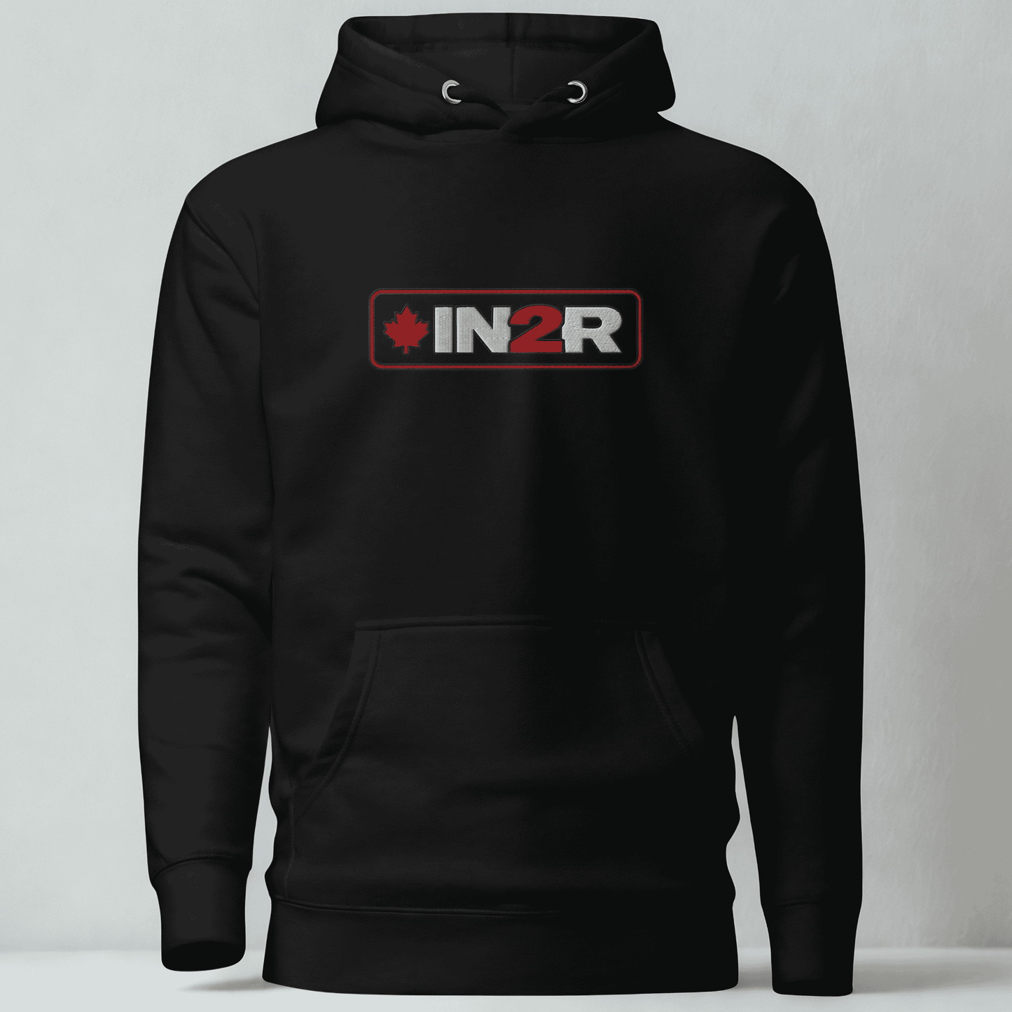 A black pullover hoodie with a front kangaroo pocket and a chest graphic that reads 'IN2R' with a red maple leaf icon, shown against a light gray background.