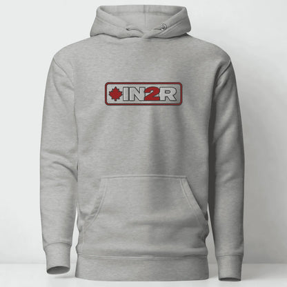 A light gray heather pullover hoodie with a front kangaroo pocket and a chest graphic that reads 'IN2R' with a red maple leaf and red border, shown on a plain light gray background.