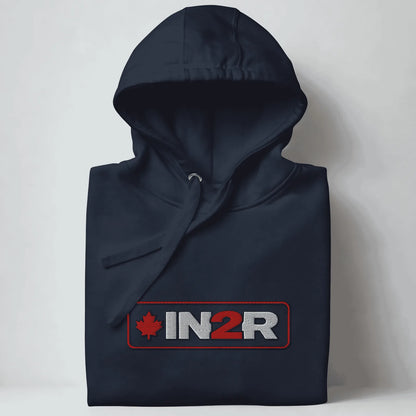 A folded navy blue hooded sweatshirt with a drawstring hood and a front graphic reading 'IN2R' in white and red with a red maple leaf, shown against a light gray background.