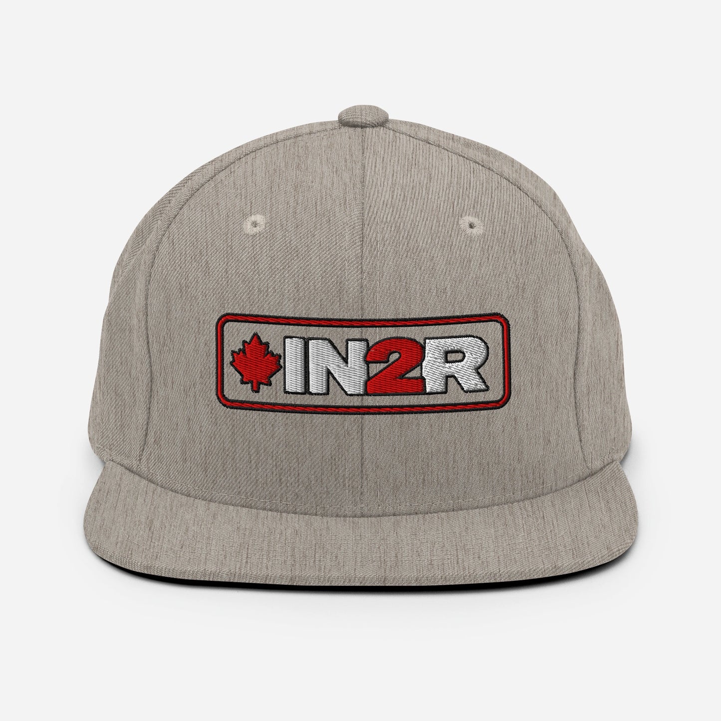 A heather gray snapback cap featuring a rectangular embroidered patch on the front with a red maple leaf, the text 'IN2R' in white and red, and a red border.