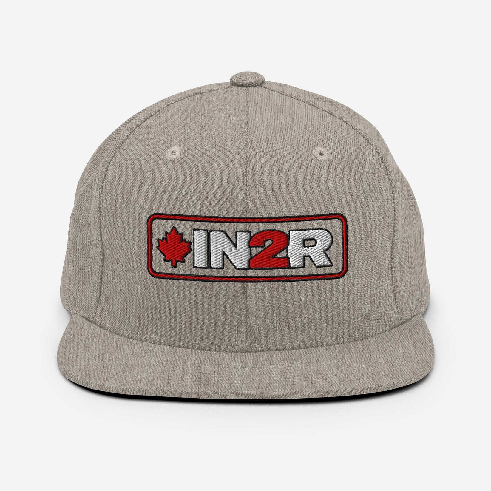 A heather gray snapback cap featuring a rectangular embroidered patch on the front with a red maple leaf, the text 'IN2R' in white and red, and a red border.