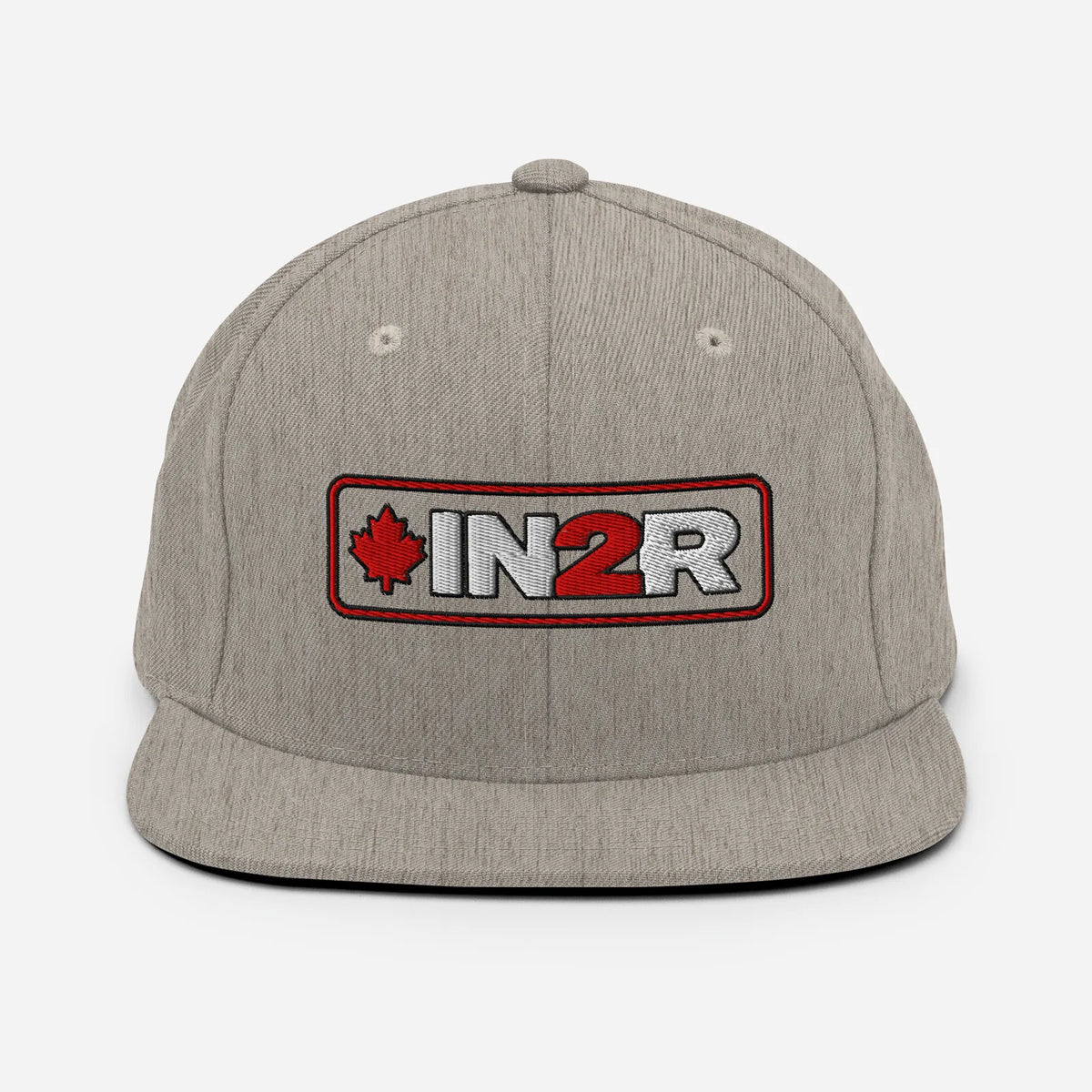 A heather gray snapback cap featuring a rectangular embroidered patch on the front with a red maple leaf, the text 'IN2R' in white and red, and a red border.