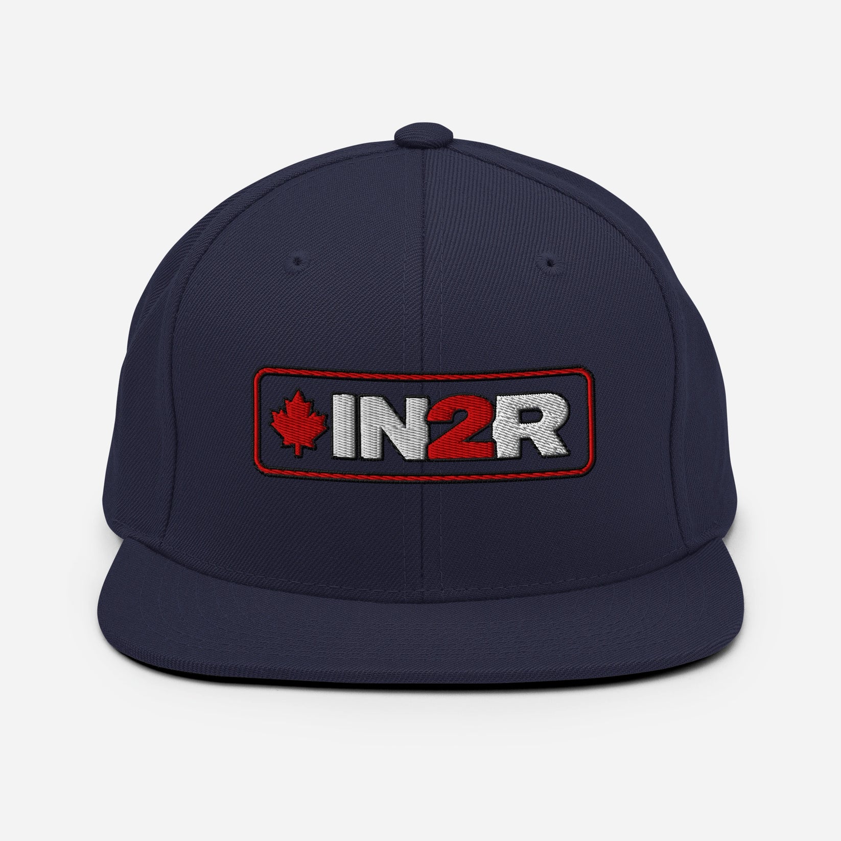 A navy blue flat-brim snapback cap featuring an embroidered front patch with a red maple leaf, the text 'IN2R' in white and red, and a red border.