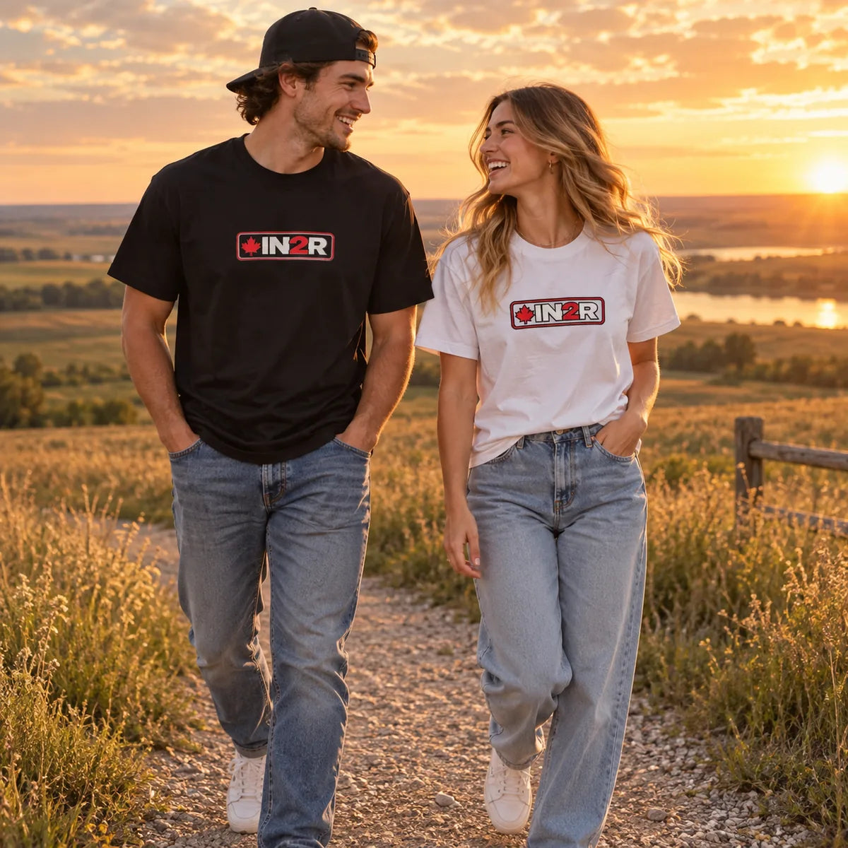Couple wearing IN2R Canadian Edition tees while walking through a Saskatchewan prairie landscape at sunset.