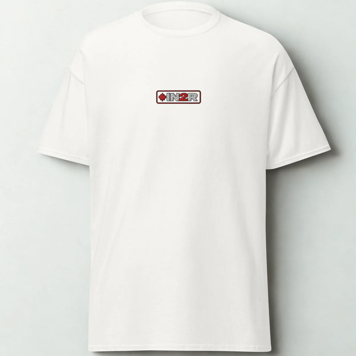 A white short-sleeve crewneck t-shirt with a small rectangular chest graphic featuring the brand name 'IN2R' and a red maple leaf, displayed against a light gray background.