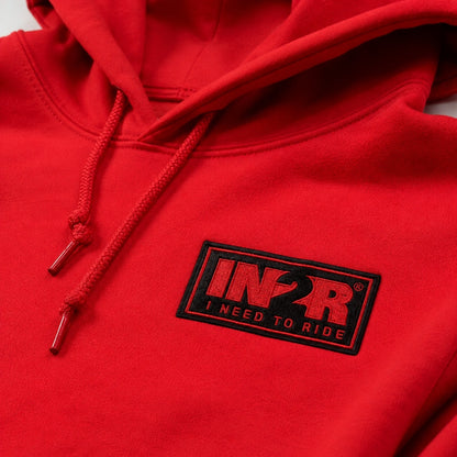 Close-up of the embroidered IN2R I Need To Ride logo patch on the Classic Red Unisex Hoodie, highlighting premium stitching and fabric detail.