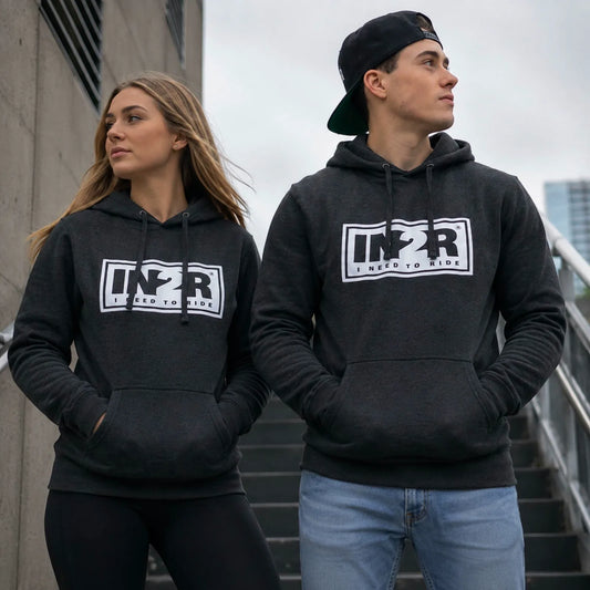 Two models wearing matching dark gray heather pullover hoodies with a white and black 'IN2R' graphic on the chest, standing on outdoor stairs.
