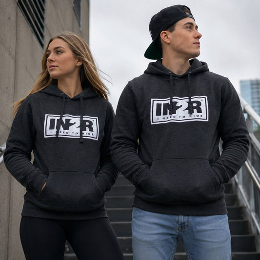 Two models wearing matching dark gray hoodies with a white and black 'IN2R' graphic on the chest, standing outdoors on a staircase.