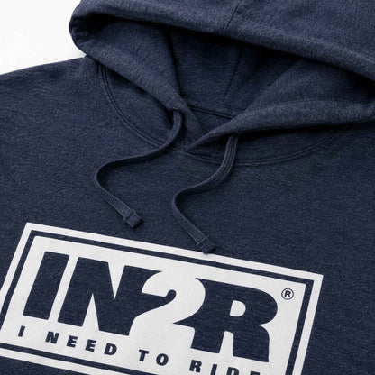 Close-up of a navy blue heather hoodie featuring a white rectangular graphic on the chest with the text 'IN2R' and 'I NEED TO RIDE'.