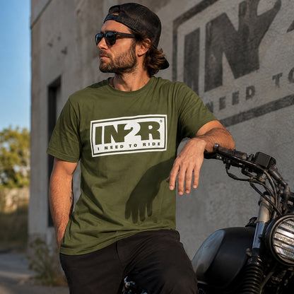 IN2R Original Moss Green Unisex T-Shirt worn by a model beside a motorcycle, showcasing the premium olive green graphic tee with oversized white IN2R logo in an urban lifestyle setting.