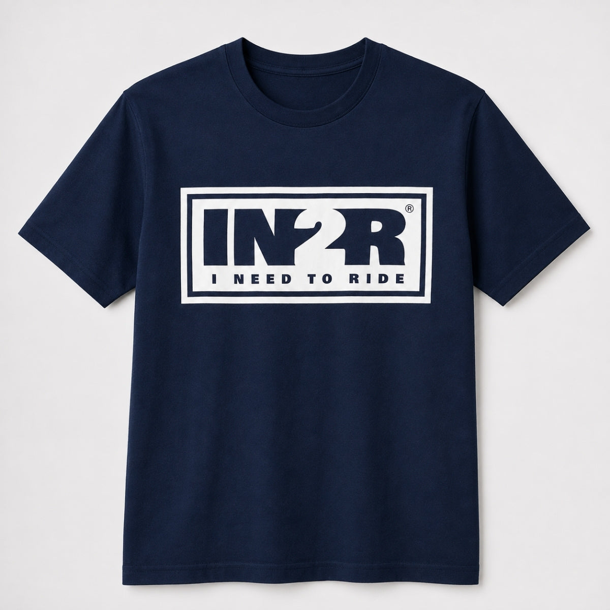 A navy blue short-sleeve crewneck t-shirt with a white graphic print on the chest that reads 'IN2R I NEED TO RIDE' inside a white rectangular border.