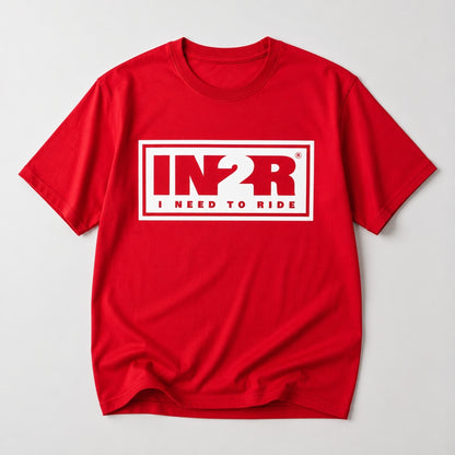 A red short-sleeve crewneck t-shirt with a white graphic print on the chest reading 'IN2R I NEED TO RIDE' inside a white rectangular border, shown on a light gray background.