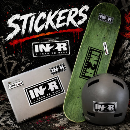 A promotional product shot showing multiple IN2R stickers applied to a green skateboard deck, a silver laptop, and a dark gray helmet. Large white 'STICKERS' text appears at the top over a dark graphic background.