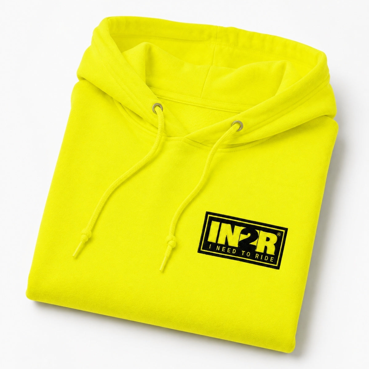 A folded neon yellow hoodie with a black and yellow 'IN2R I NEED TO RIDE' logo patch on the chest, shown on a clean white background.