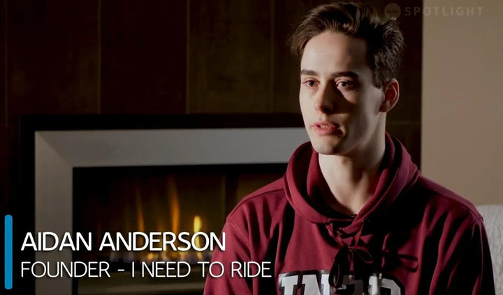 Aidan Anderson, founder of the band Need to Ride, wearing a maroon hoodie and looking off-camera in an indoor setting with a fireplace in the background. Text overlays identify him and his role, with a 'SPOTLIGHT' logo in the top right corner.