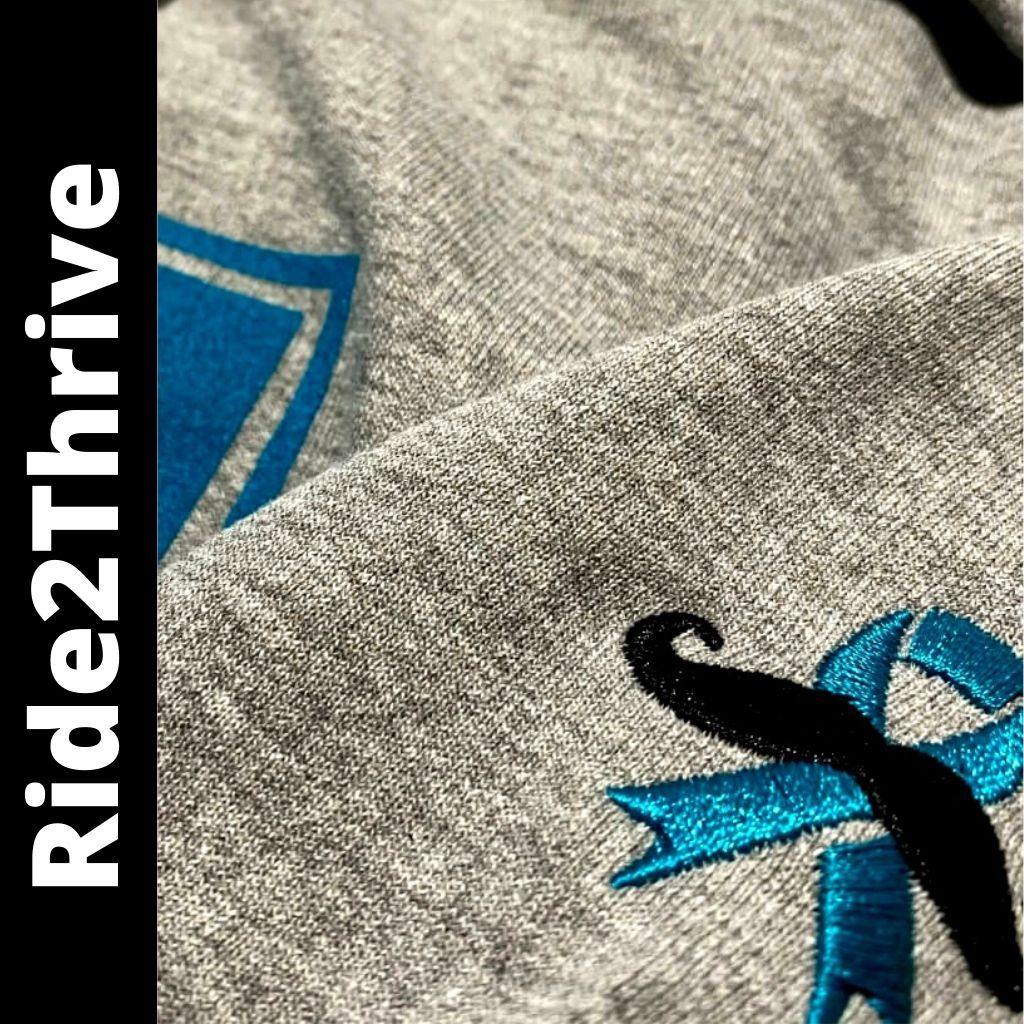 Athletic heather IN2R Ride2Thrive unisex hoodie with embroidered men’s health ribbon on the sleeve
